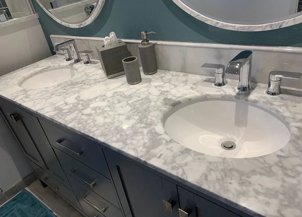 Double sink marble countertop vanity with chrome fixtures in remodeled bathroom