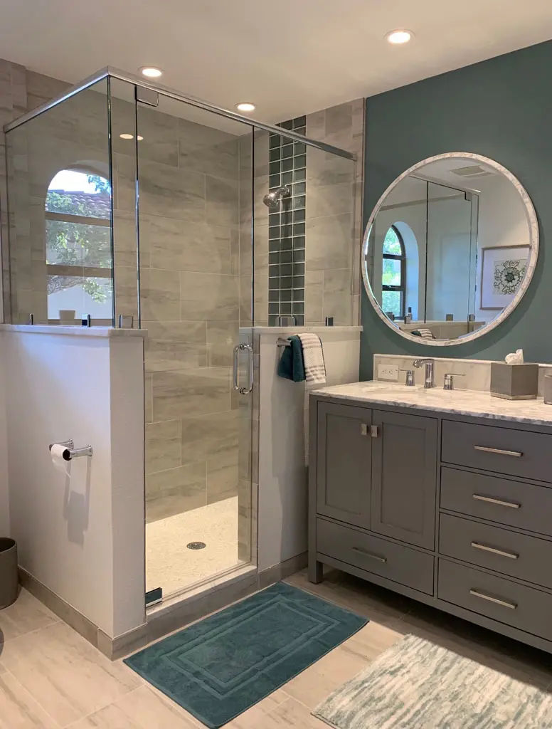 Glass shower enclosure with tile surround and gray vanity bathroom renovation