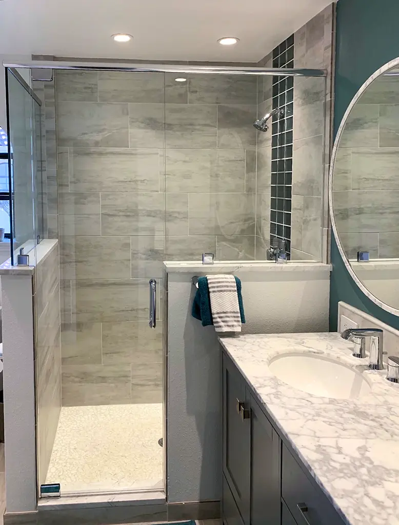 Tile walk-in shower with glass door and marble vanity countertop