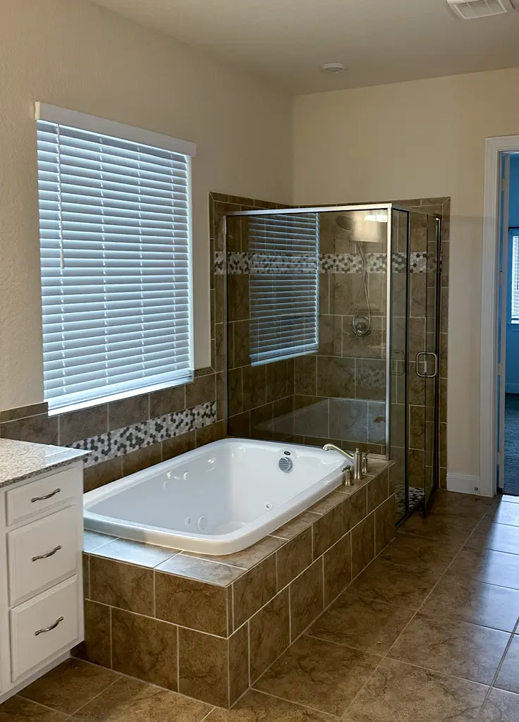 Master bathroom before remodel with dated garden tub and brown tile shower in San Antonio