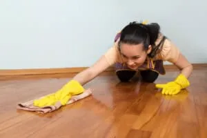Hand cleaning water spill on hardwood floor for proper maintenance